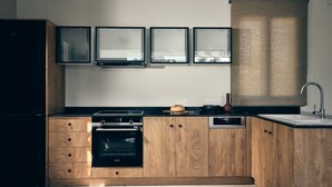 A modern kitchen with wooden cabinets, a built-in oven, a stovetop, and a sink.