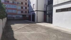 A narrow street with a gated entrance leading to a building with multiple windows and a gated driveway. - Piso a pie de Playa (Suances)
