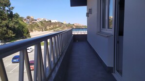A balcony with a view of a beach and buildings in the distance. - Piso a pie de Playa (Suances)