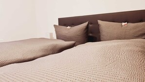 Una cama con una cubierta marrón texturizada y dos almohadas.