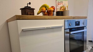 Una cocina compacta con un refrigerador blanco, un horno empotrado y una encimera de madera.