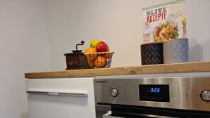 Una cocina con un refrigerador blanco, un horno de acero inoxidable y un reloj digital que marca las 3:02.