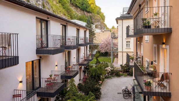 Un patio con varios balcones, mobiliario exterior y vistas a un promontorio rocoso.