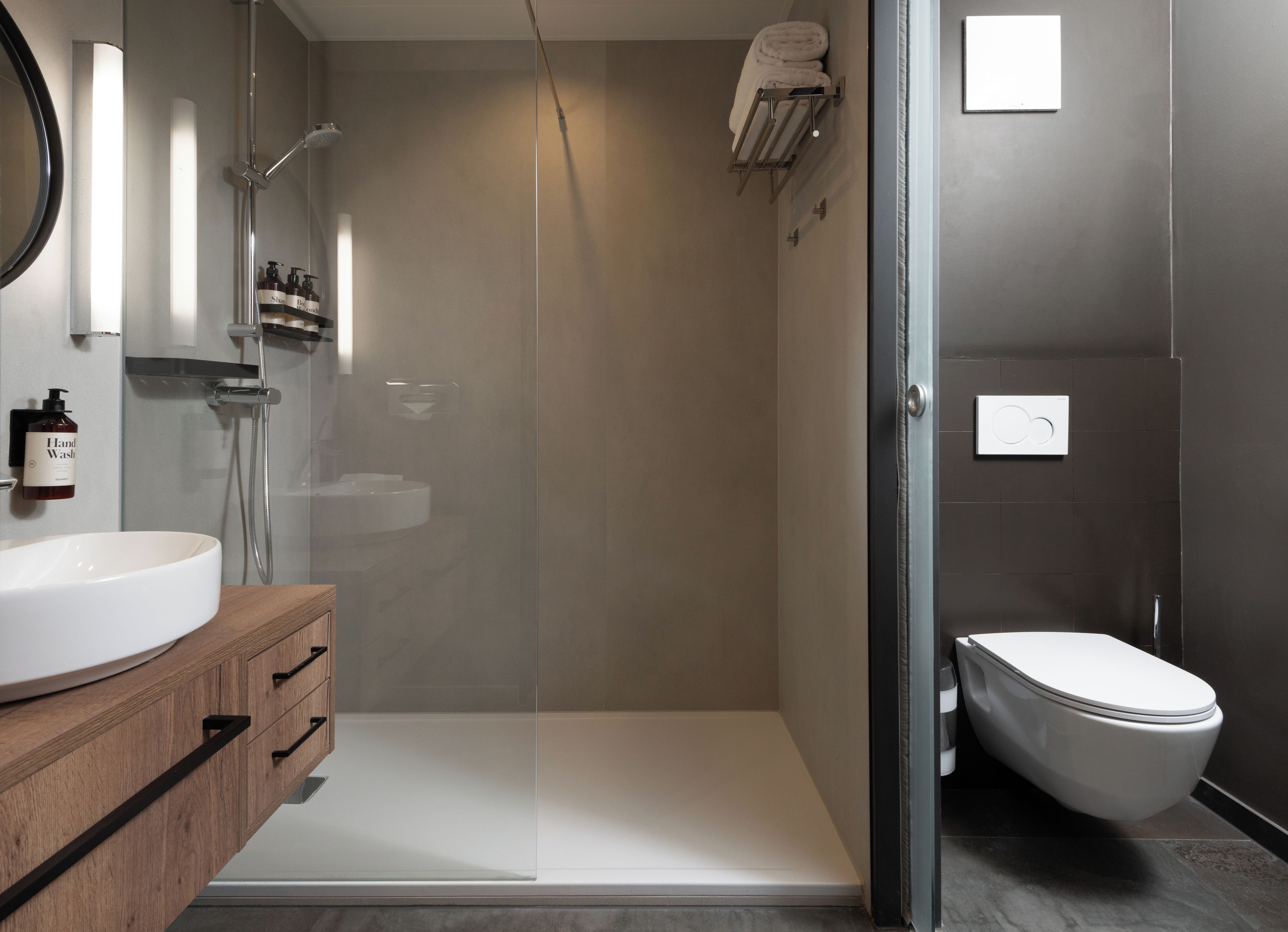 A modern bathroom with a glass-enclosed shower, a white sink, and a toilet.