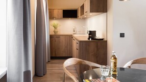 Una cocina moderna con armarios de madera, una mesa de comedor con sillas y un amplio ventanal con cortinas.