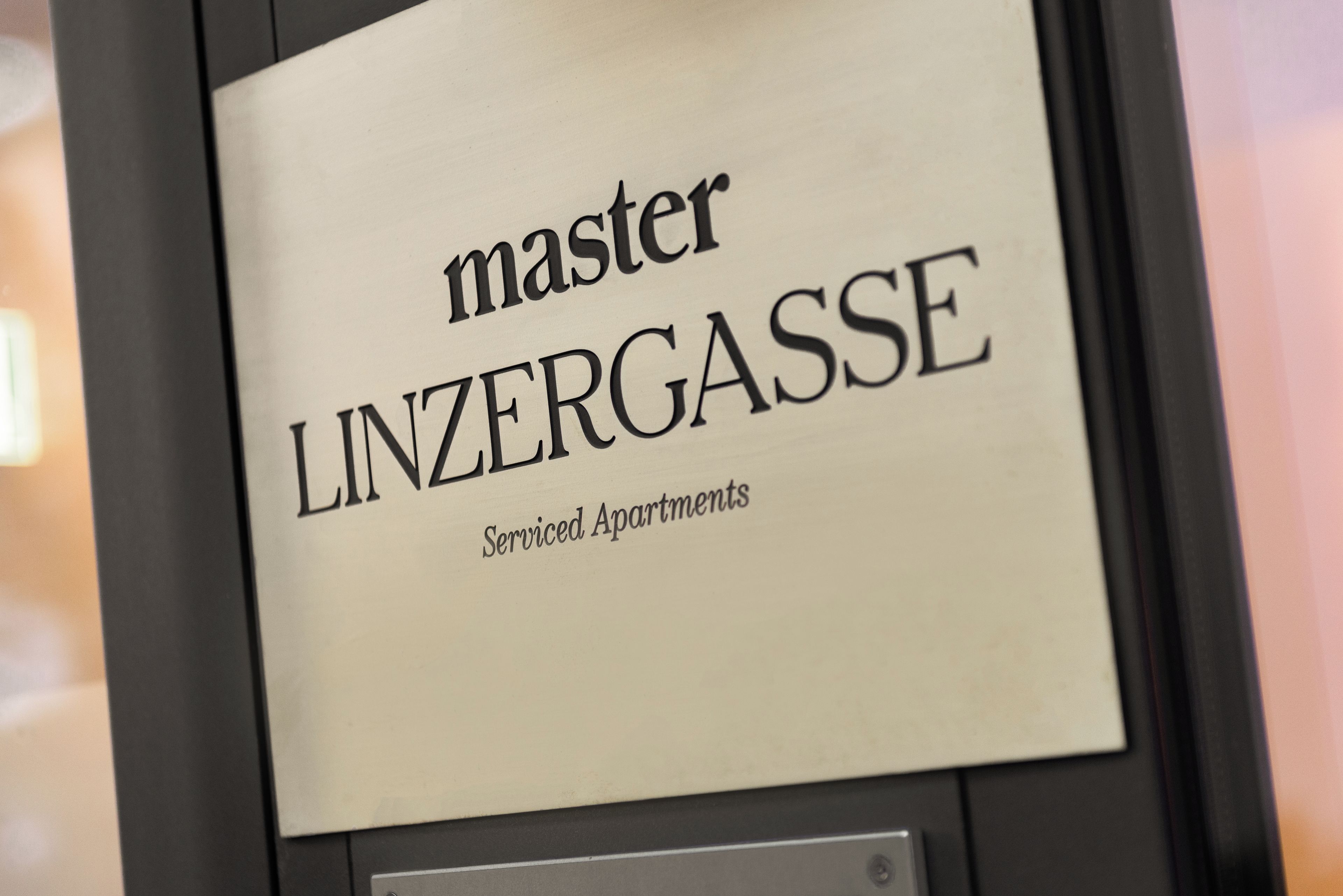 A sign with the text 'master LINZERGASSE Serviced Apartments'.
