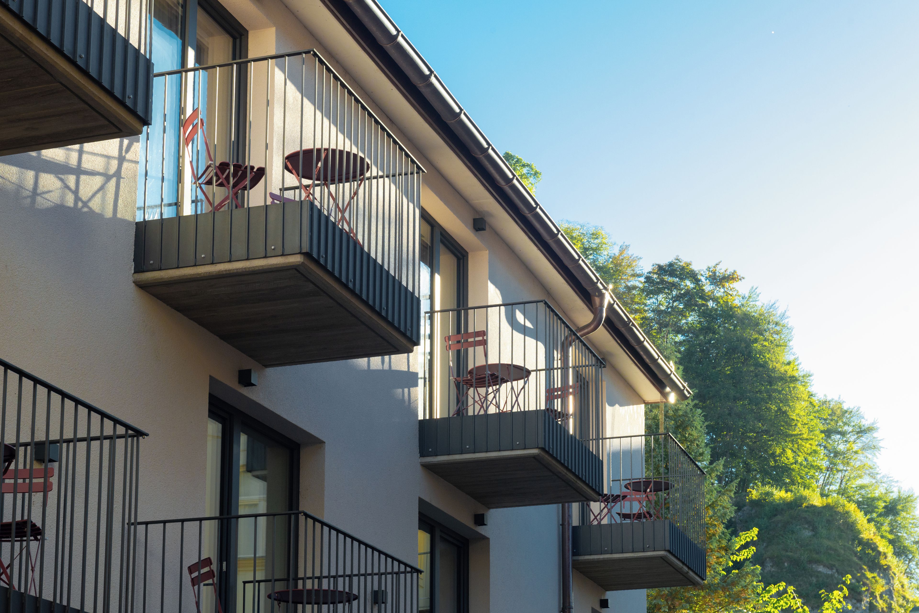 A multi-story building with balconies, each equipped with a chair and a table.