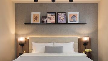 A neatly arranged bedroom with a bed, two bedside tables, and a wall-mounted shelf with framed pictures.