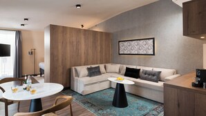 Una sala moderna con un sofá seccional color beige, una mesa de comedor redonda y una máquina de café sobre una encimera de madera.