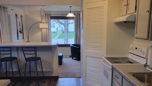 A kitchen with wooden flooring, a stove, cabinets, and a window with a view of the outside. - Dog-Friendly, Fenced-In Backyard, Quiet Neighborhood (Sturgeon Bay)