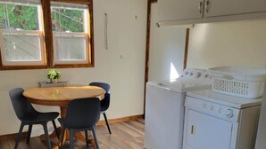 A kitchen with a wooden dining table, two chairs, a washing machine, and a dryer. - Dog-Friendly, Fenced-In Backyard, Quiet Neighborhood (Sturgeon Bay)