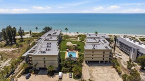 Um hotel com piscina no terraço, vista para a praia e vários edifícios com aparelhos de ar condicionado.