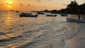 A beach with boats and a sunset. - Diamond Plaza Beachfront Apartment  (Grand Anse)