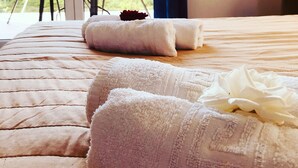 A bed with neatly folded white towels and a rose. - Banos apartments and swimming  pool (Corfu)