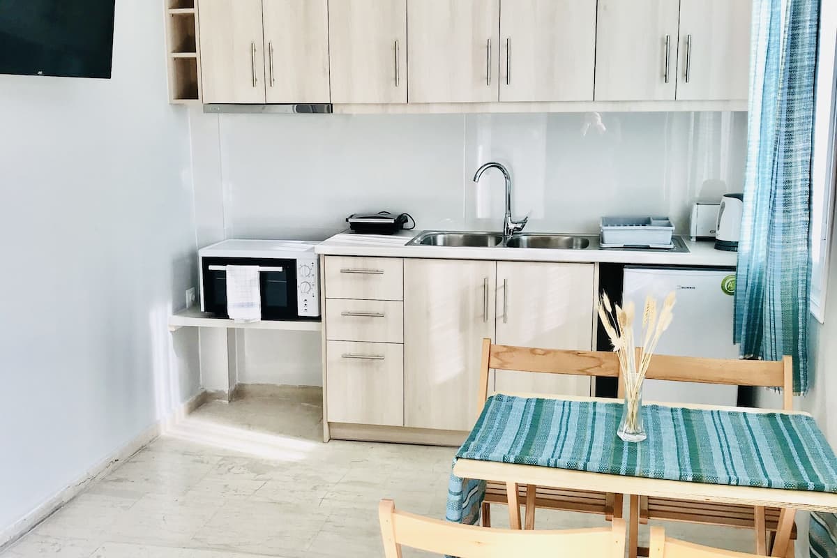 A modern kitchen with light wooden cabinets, a white countertop, and a hanging pendant light.