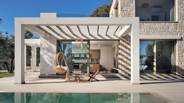 A modern house with a pool, a hanging chair, and a stone wall. - Metis Villa, a Luxury Retreat (Zakynthos)