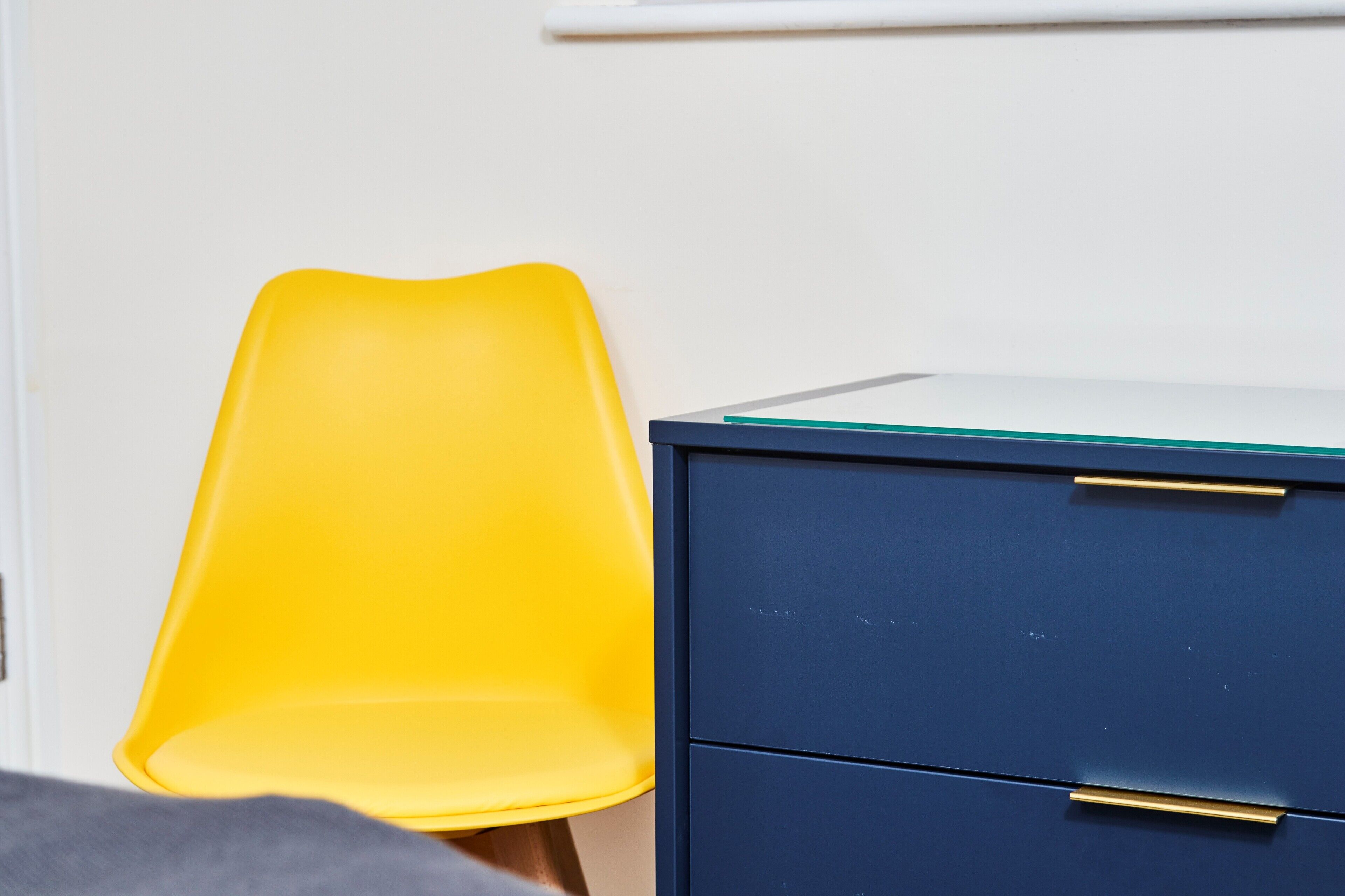 A room with a yellow chair and a blue filing cabinet.