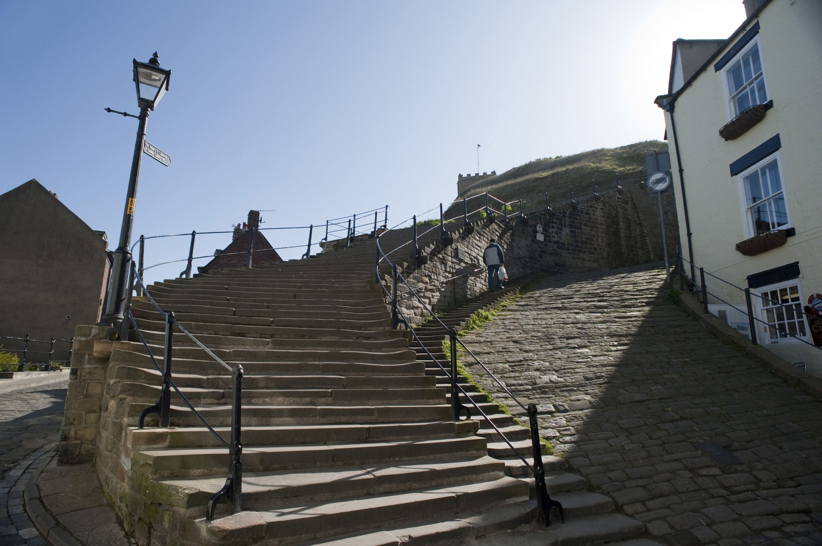 A stone staircase leading up to a hill with a view of a building.