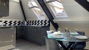 A modern kitchen with skylights, a dining area with a glass table, and a view of the outside through the skylights. - Whitby Bridge Luxury Apartments (Whitby)