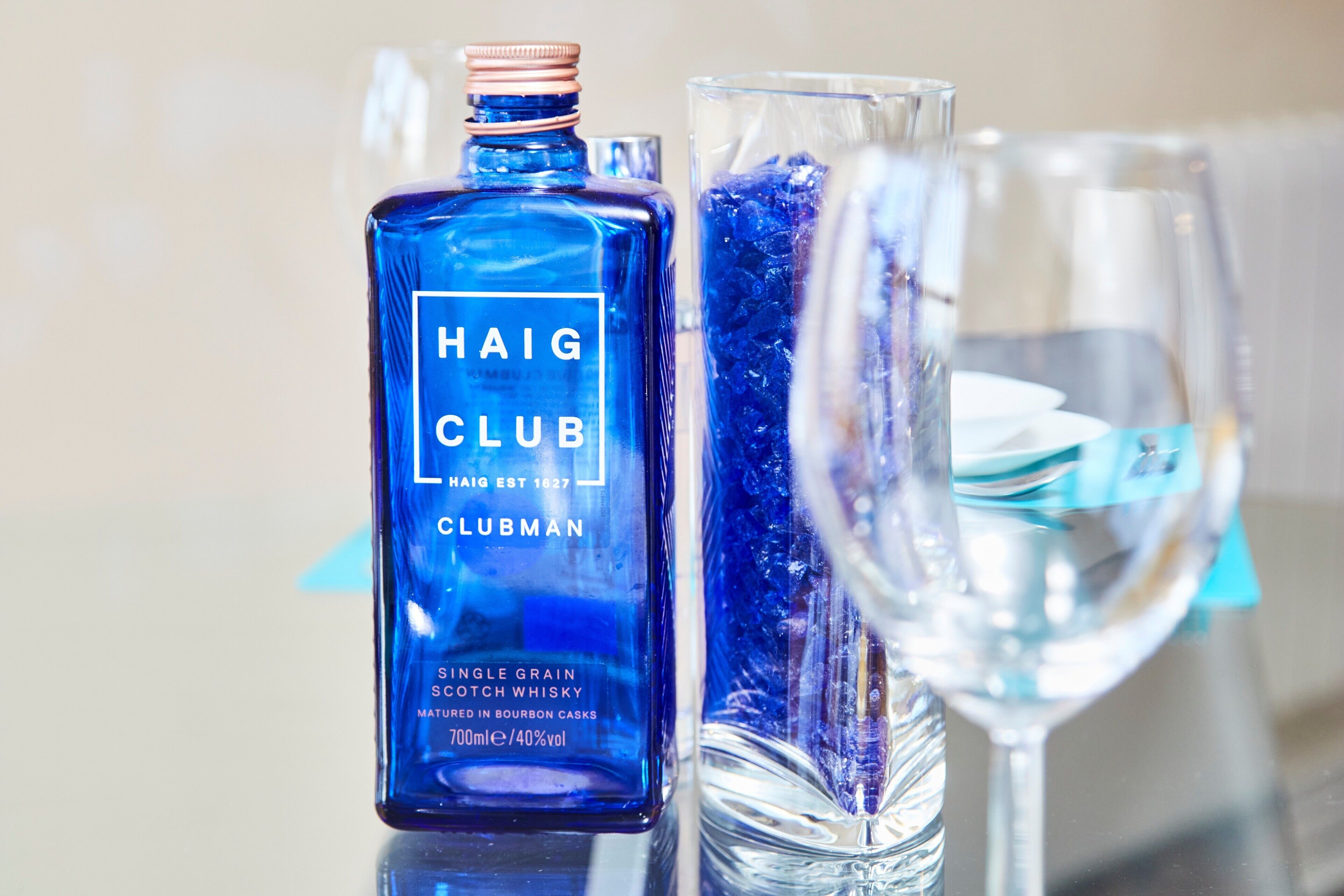 Una botella de whisky escocés Haig Club Clubman y un vaso con cubitos de hielo.