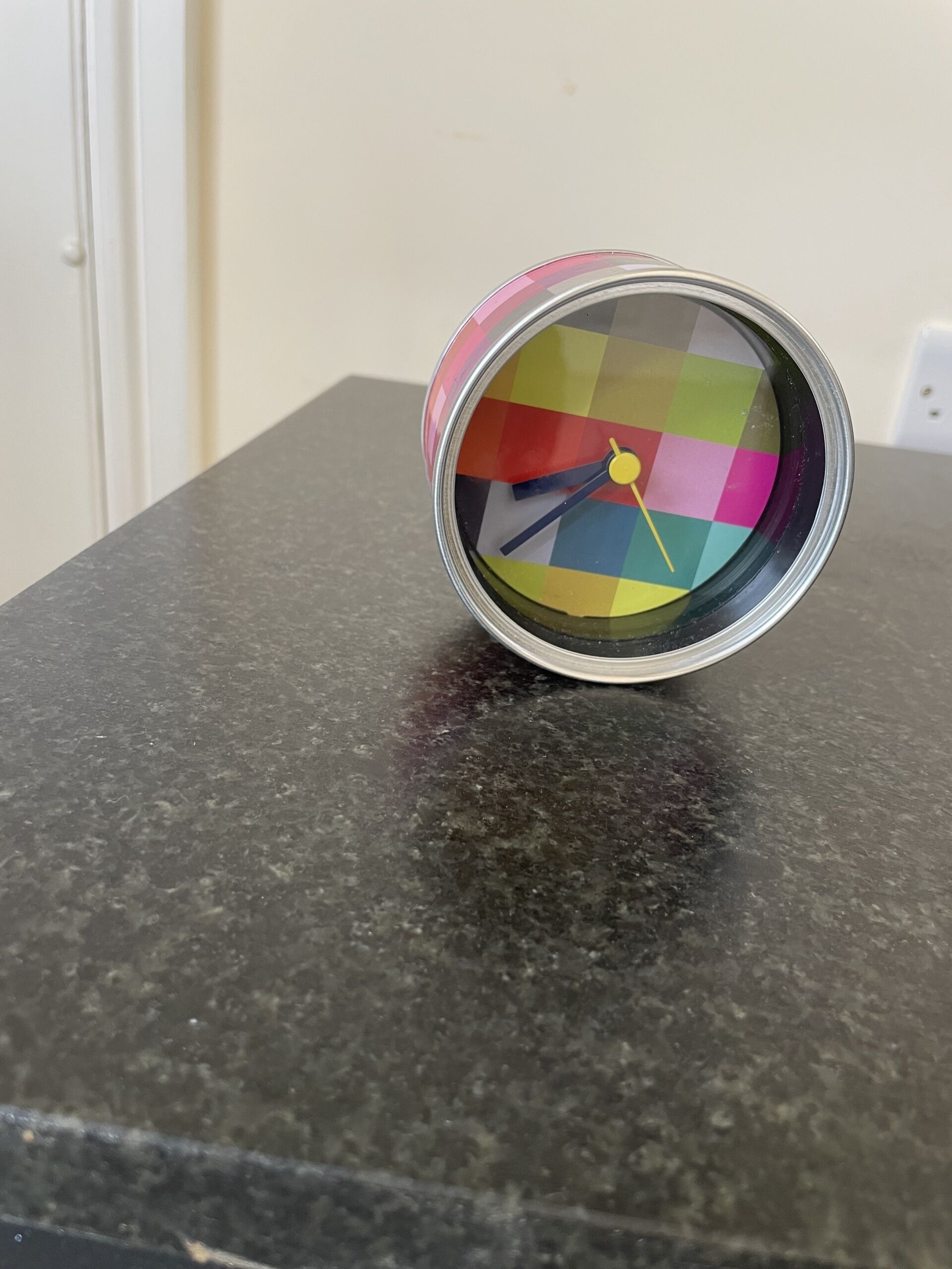 Un reloj colorido sobre una encimera oscura.