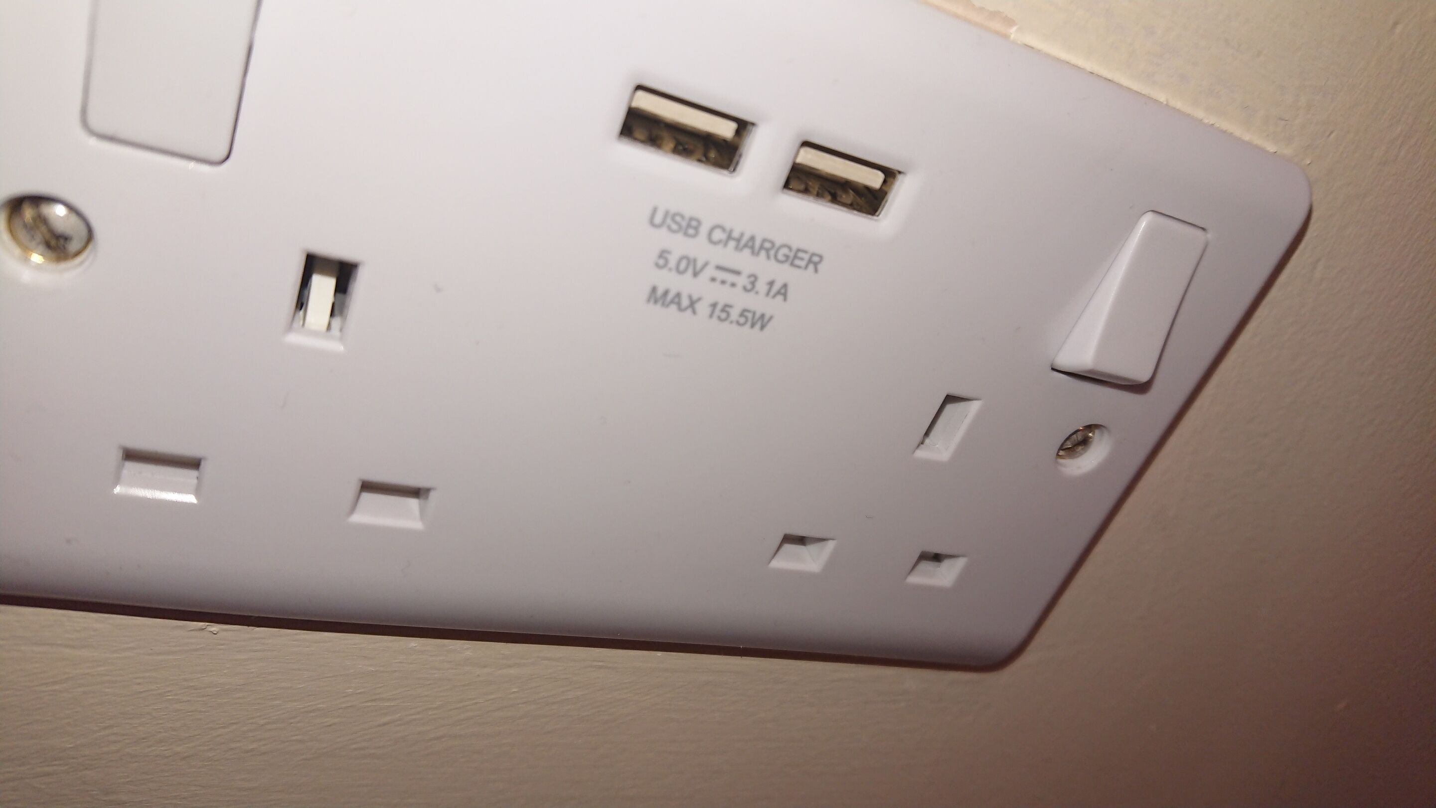 Um carregador USB branco com duas entradas USB e um indicador luminoso de energia.