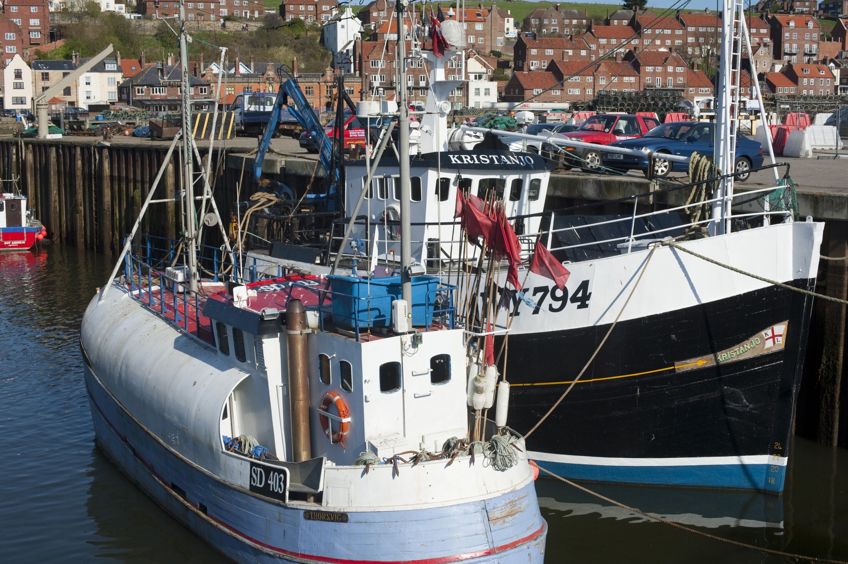 A large boat docked at a pier with a town in the background.