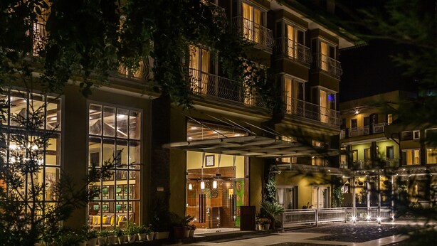Un hotel de varios pisos con un espacio exterior cubierto, ventanas amplias y balcones.