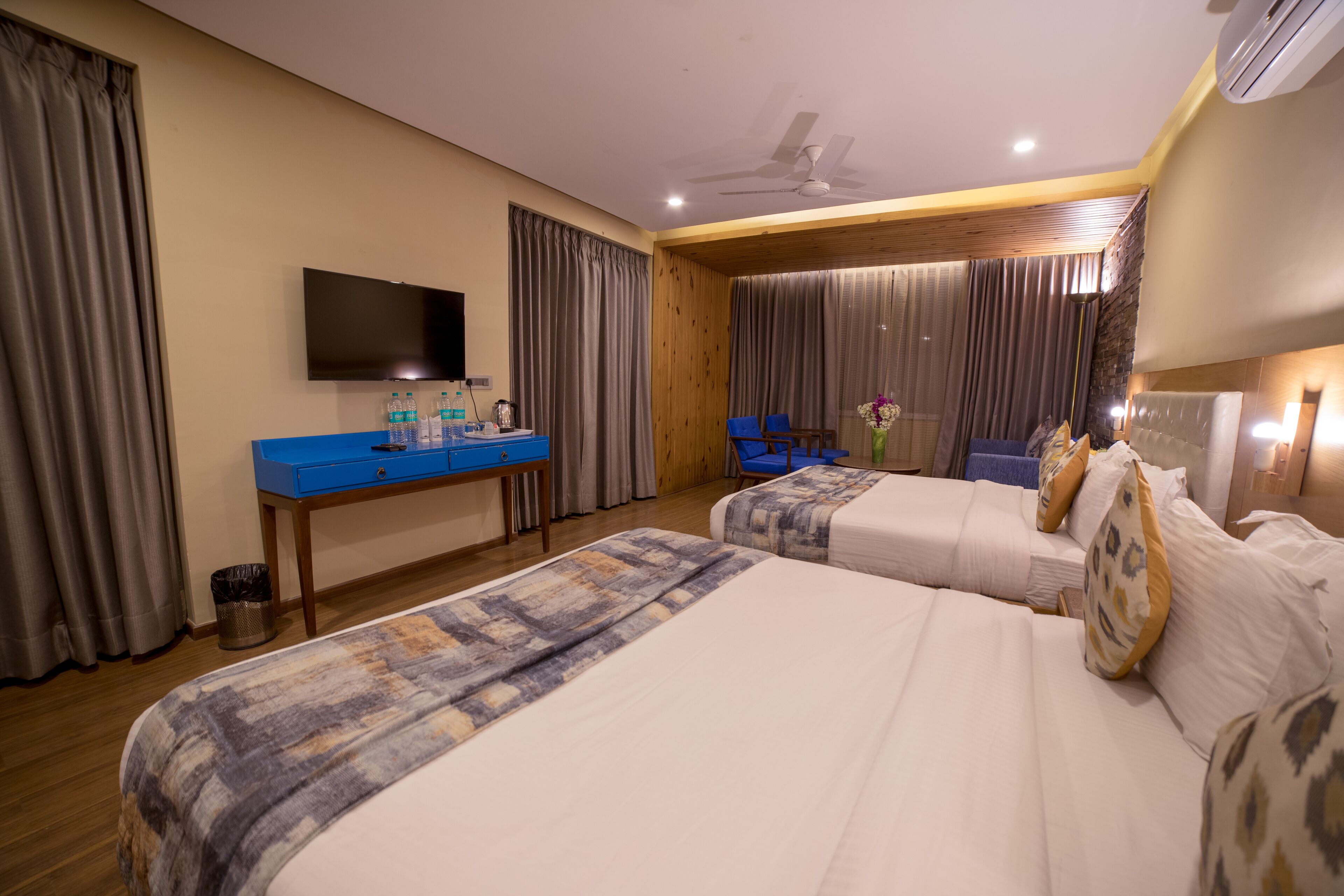 A hotel room with two beds, a desk with a flat-screen TV, and a chair.