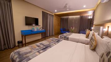 A hotel room with two beds, a desk with a flat-screen TV, and a chair.