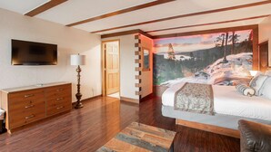 Ein Schlafzimmer mit Bett, Kommode, Fernseher und einem Wandbild eines Wasserfalls.