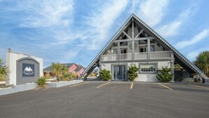 A modern building with a unique triangular roof and a parking lot in front. - Flip Flop - Queen Studio Room at Wanderlust Inn, Pet Friendly (Ocean Shores)