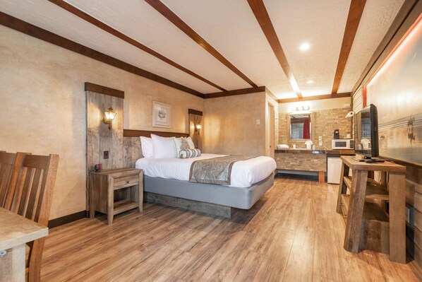 A bedroom with a large bed, wooden headboard, bedside tables, a desk, and a television.