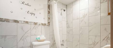 Een badkamer met toilet, bad en douchegordijn.