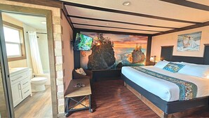 Een slaapkamer met een bed, een televisie, een bureau en uitzicht op de oceaan.