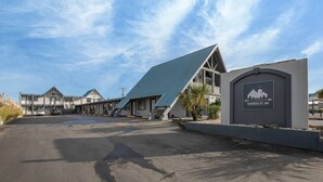 A building with a unique sloped roof and a sign for the Wanderlust Inn. - Sea Dreamer - 1 Bedroom Suite with 1 King and 1 Queen Bed at Wanderlust Inn, Pet Friendly (Ocean shores)