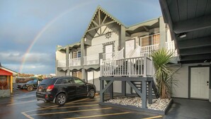 A building with a balcony, a parking lot, and a rainbow. - Once Upon a Tide - Queen Studio Room at Wanderlust Inn, Pet Friendly (Ocean shores)