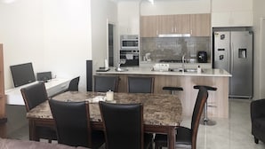 A modern kitchen with a central island, dining table, and chairs. - New Serene 4 bedroom home (Kambah)