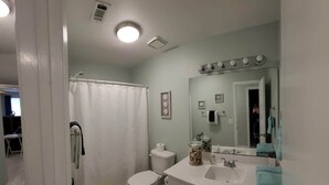 A bathroom with a shower, toilet, sink, and vanity.