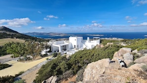 A white building with a flat roof, surrounded by greenery and rocky terrain, overlooking a coastline. - La Vue-Boule (Paros)