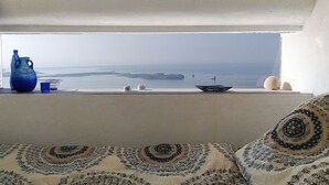 A room with a view of the sea, a window sill with decorative items, and patterned cushions. - Luxury Private Villa with Infinity Pool & Sunset Sea Views & SPA (Paros)