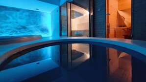 A modern interior with a glass balustrade, wooden flooring, and a blue-lit wall. - Luxury Private Villa with Infinity Pool & Sunset Sea Views & SPA (Paros)