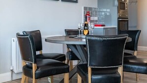 Un comedor con una mesa redonda, sillas negras y tres cuadros enmarcados en la pared.