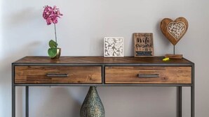 Ein Holzkonsolentisch mit Vase, gerahmten Kunstwerken und Dekorationselementen.