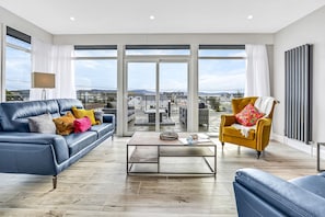 Una sala moderna con un sofá azul, un sillón amarillo y una mesa de centro.