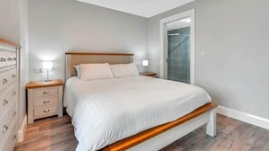 Un dormitorio con cama, mesitas de noche, cómoda y espejo.