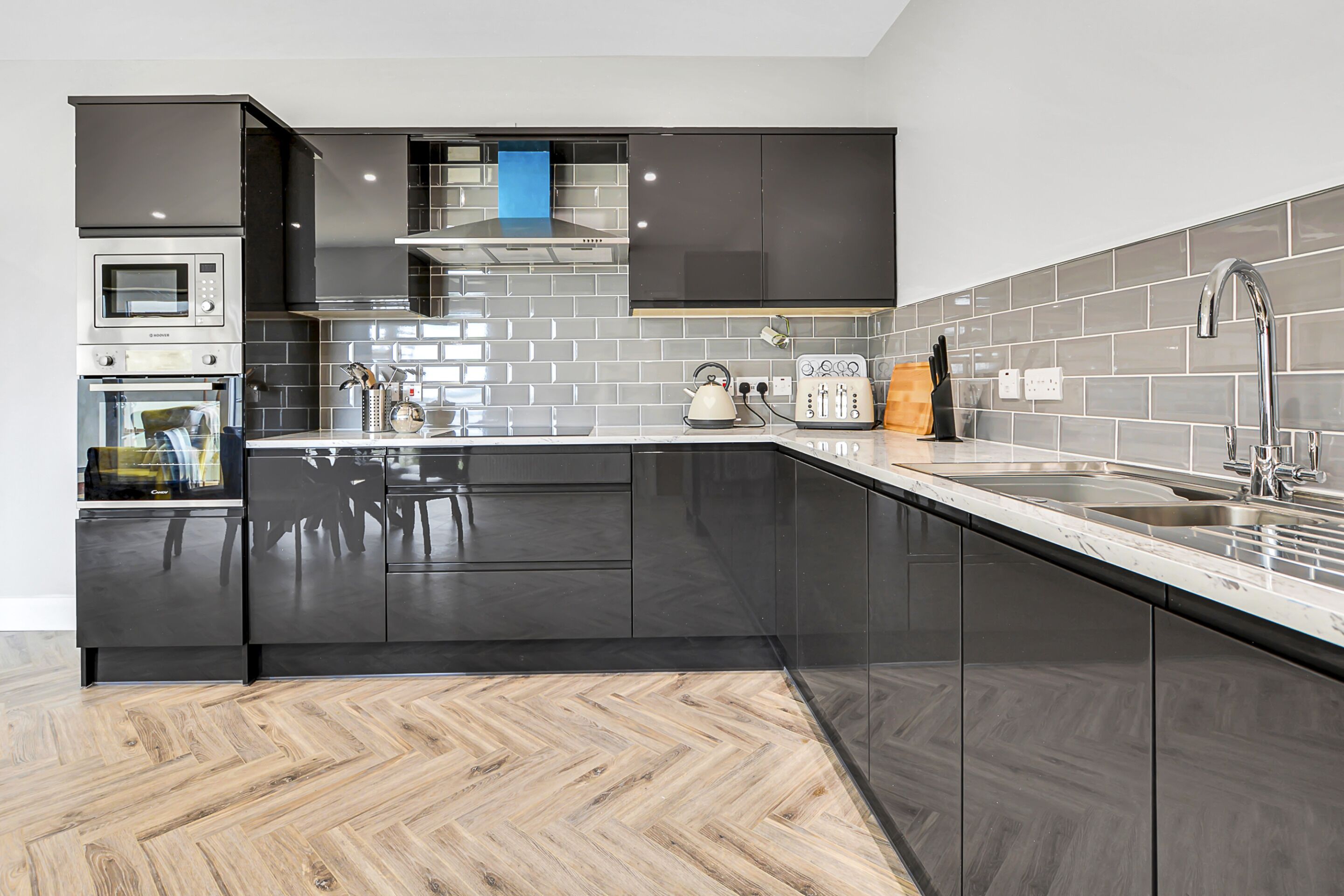 A modern kitchen with black cabinets, a microwave, oven, and a sink.
