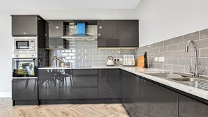 Une cuisine moderne avec des meubles de couleur noire, un four à micro-ondes, un four traditionnel et un évier.