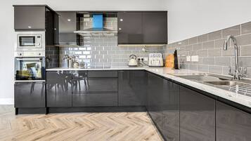 A modern kitchen with black cabinets, a microwave, oven, and a sink.