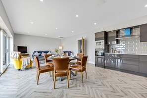 Una sala moderna con comedor, cocina con electrodomésticos de acero inoxidable y un amplio ventanal que proporciona luz natural.